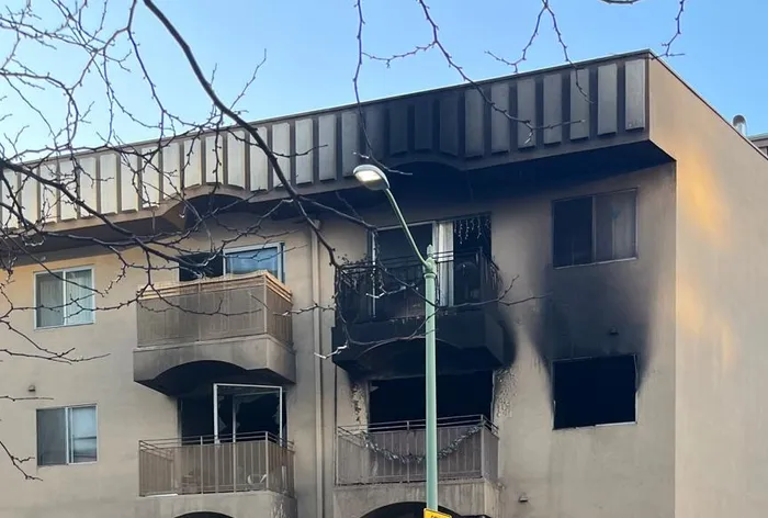 Apartment building with fire and smoke damage on the upper floors.