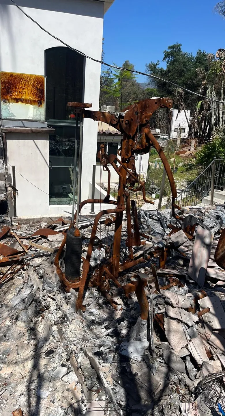 Burned exercise equipment in the ash of a destroyed home.