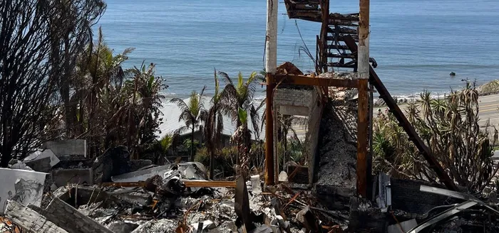 Fire-damaged coastal home reduced to its frame and rubble.