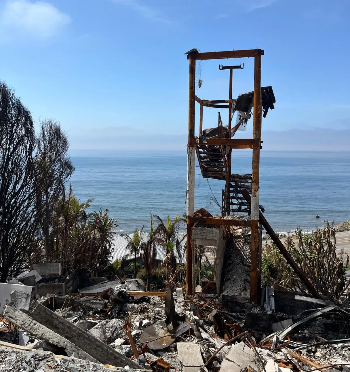 Fire-damaged coastal home reduced to its frame and rubble, field photograph.