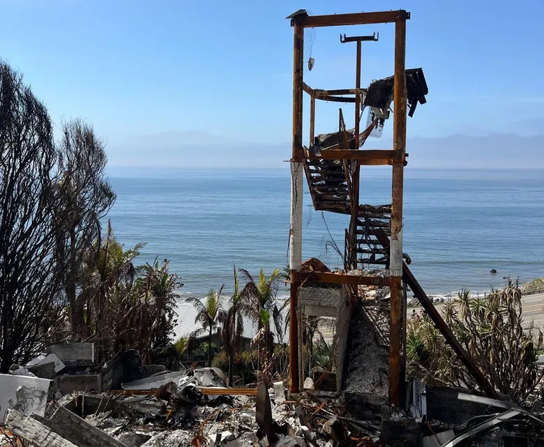 Fire-damaged coastal home reduced to its frame and rubble.