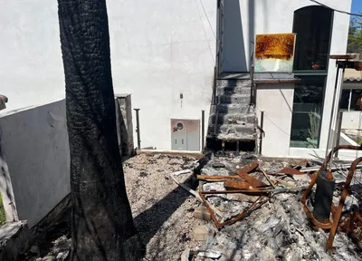 Modern home exterior after a fire, debris in the foreground