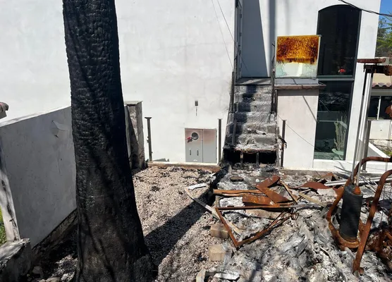 Modern home exterior after a fire, debris in the foreground