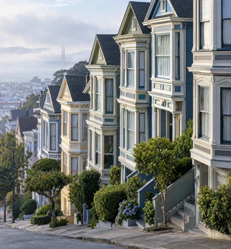 Row of Victorian houses on a hill in fog.