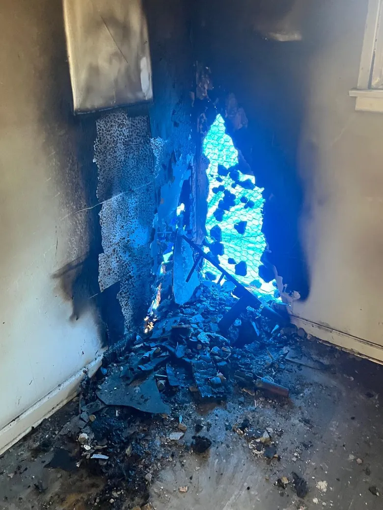 Corner of a room after a house fire, soot and smoke staining climbing the walls to the ceiling.