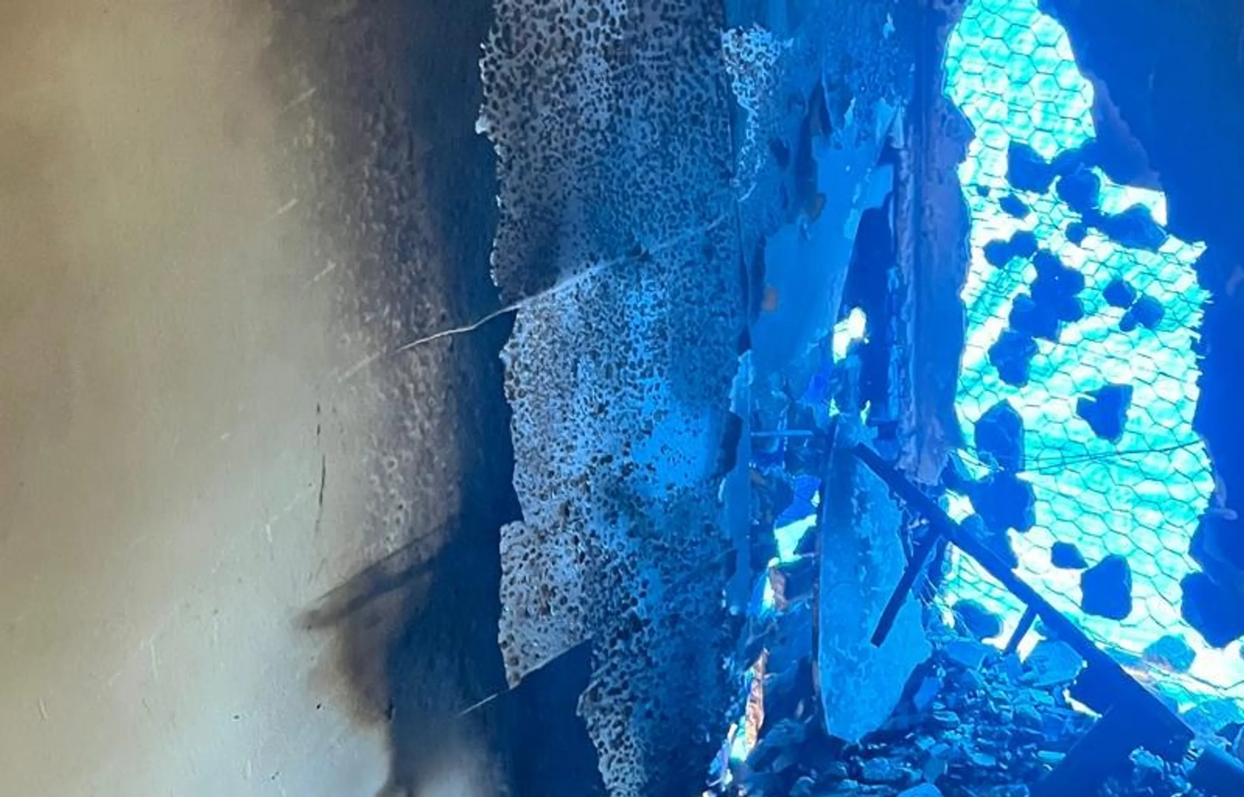 Corner of a room after a house fire, soot and smoke staining climbing the walls to the ceiling.
